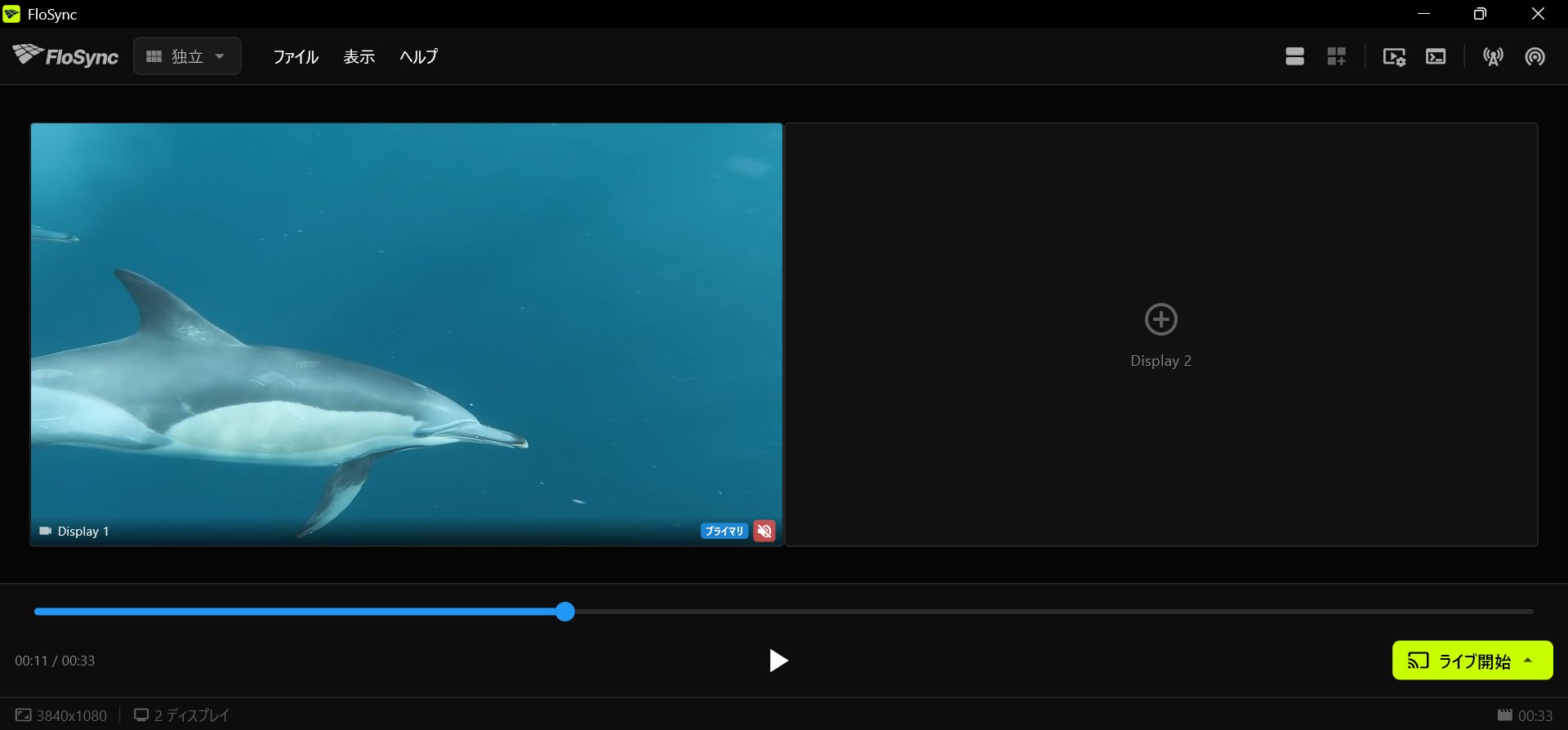 Display 1にイルカの動画が読み込まれ、Display 2はプラス記号だけの空の状態で、タイムラインが途中まで進み、下部バーに再生ボタンとライブ開始ボタンがあるFloSyncのコントロールパネル